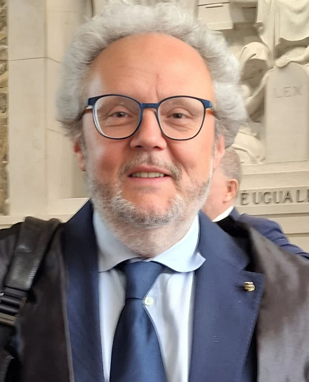Avv. Stefano Micheli, ritratto davanti a un bassorilievo del Palazzo di Giustizia di Milano