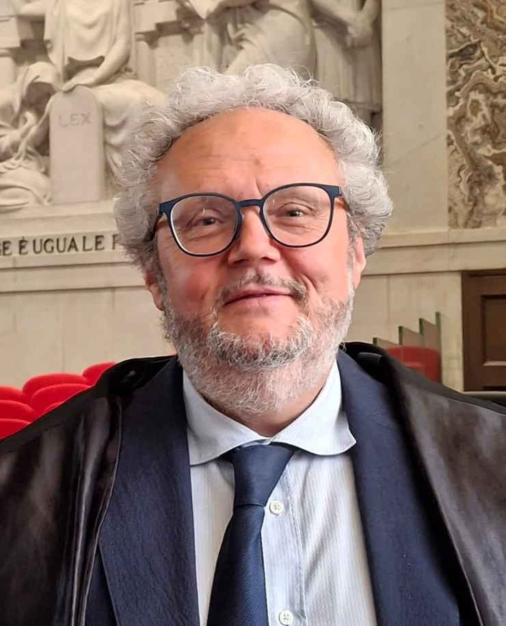 Avv. Stefano Micheli in toga, in un'aula di giustizia davanti al bassorilievo «La legge è uguale per tutti»